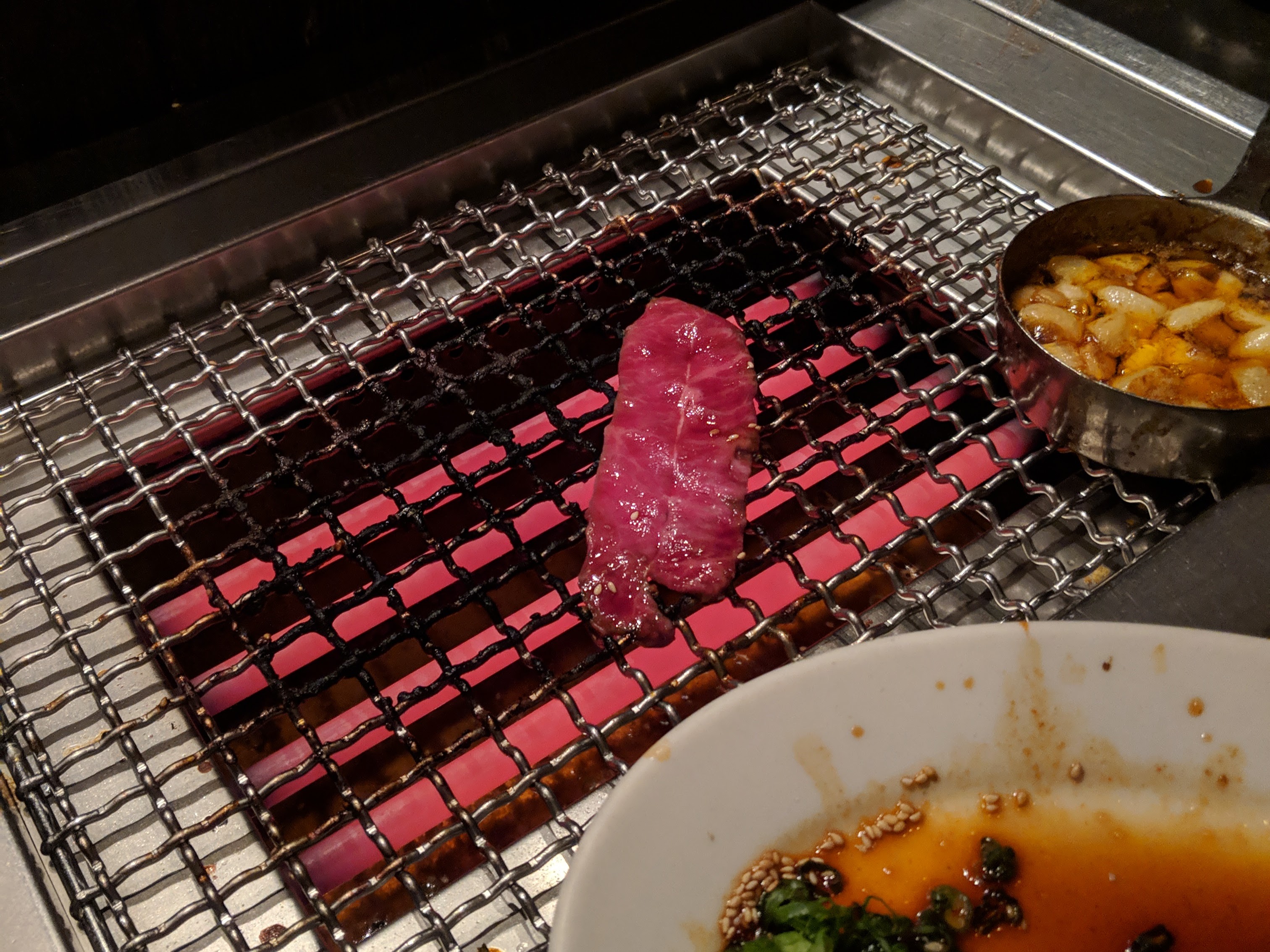 A thin slice of meat, sizzling on a personal grill.